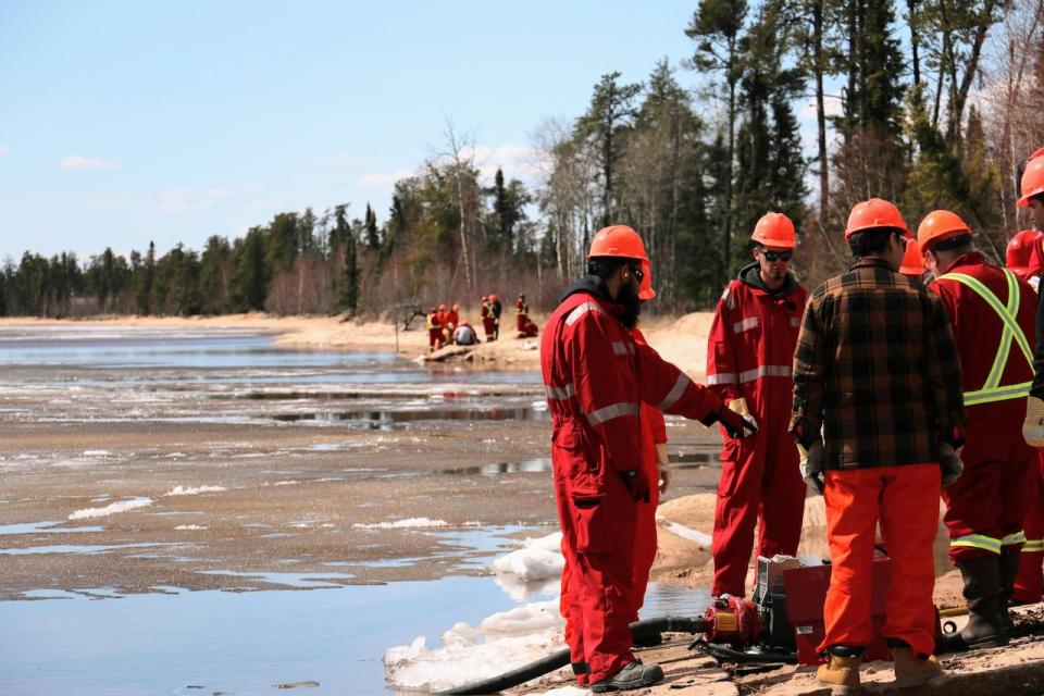 The group of trainees learns to put motors into the half-frozen Lac la Plonge. In remote areas, firefighters will often use whatever water resource is around to douse flames.