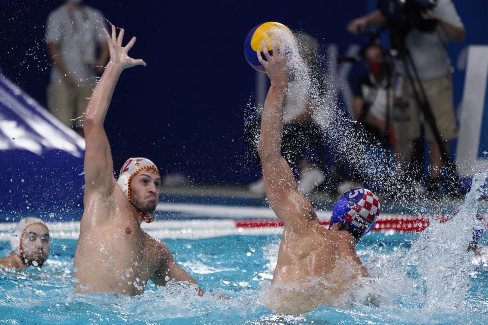 Croatia's Maro Jokovic (5) passes the ball over Spain's Alejandro Bustos Sanchez (12) during a preliminary round men's water polo match at the 2020 Summer Olympics, Monday, Aug. 2, 2021, in Tokyo, Japan. (AP Photo/Mark Humphrey)