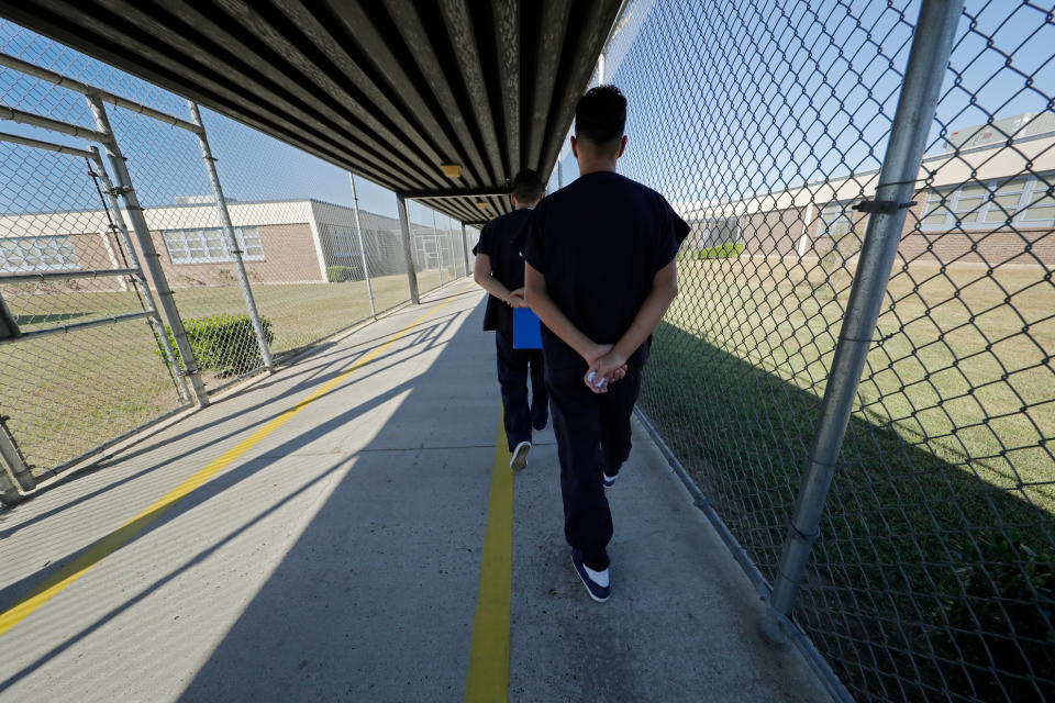 Detainees walk with their hands clasped behind their backs along a line painted on a walkway inside the Winn Correctional Center in Winnfield, La., Thursday, Sept. 26, 2019. Detainees are required to walk from site to site with their hands clasped behind their backs. Since 2018, eight Louisiana jails have started detaining asylum seekers, making Louisiana an unlikely epicenter for immigrant detention under President Donald Trump. Immigration and Customs Enforcement says it’s now detaining about 8,000 migrants in Louisiana out of 51,000 nationally. (AP Photo/Gerald Herbert)