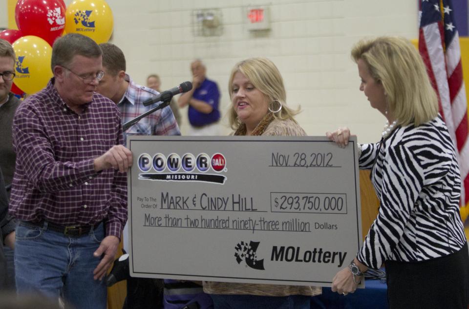 Mark, left, and Cindy, center, Hill are presented a check by a Missouri Lottery official during the announcement of Powerball winners in Dearborn, Mo., Friday, Nov. 30, 2012. (AP Photo/Orlin Wagner)