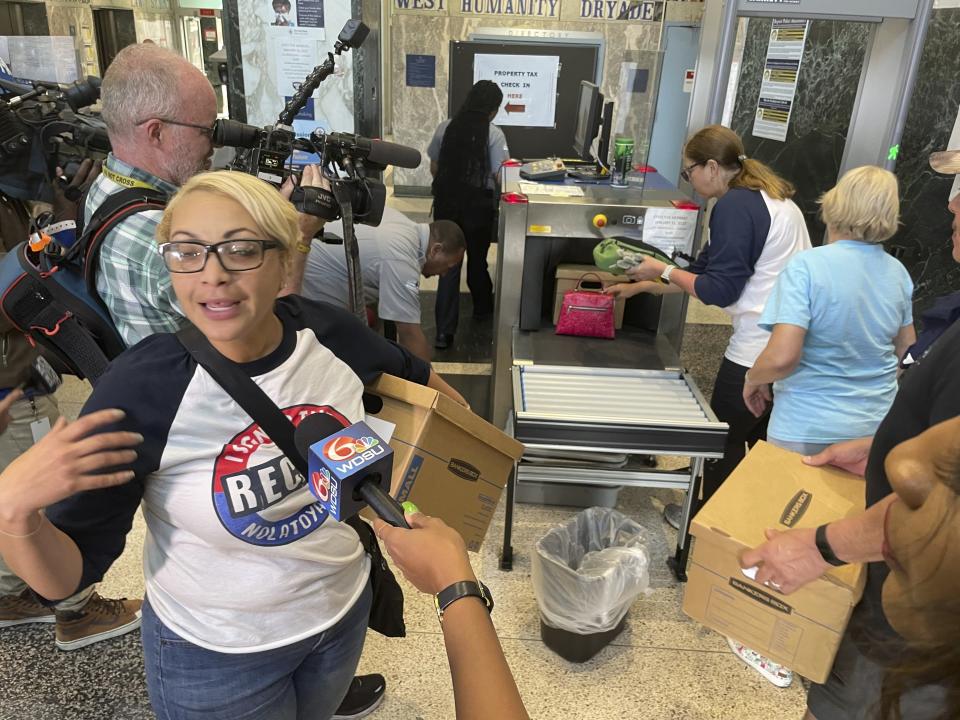 FILE - Eileen Carter, an organizer of a recall petition drive against New Orleans Mayor LaToya Cantrell, holds a box of petitions as others are put through security equipment at New Orleans City Hall, Feb. 22, 2023. A court settlement that significantly lowered the number of petition signatures Cantrell's opponents need to force a recall election was challenged by Cantrell and one of her supporters in two state courts Tuesday, March 14. (AP Photo/Kevin McGill, File)