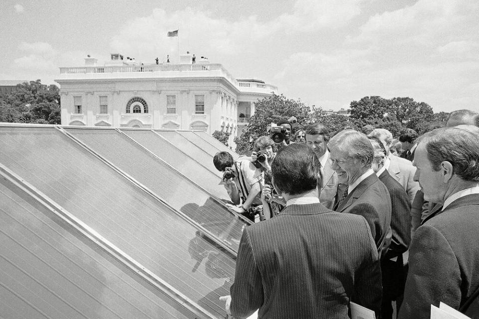 President Jimmy Carter (right) surrounded by reporters as he inspects solar panels installed at the White House during his presidency. | Harvey Georges/AP/Shutterstock