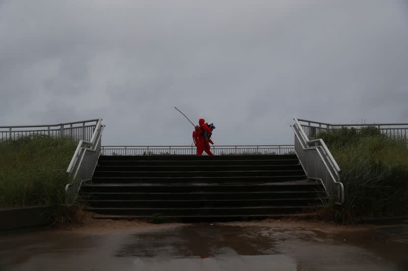 A lifeguard walks on a boardwalk, as Tropical Storm Fay was expected to sweep across the heavily populated northeastern United States, in the Rockaways section of the Queens borough of New York