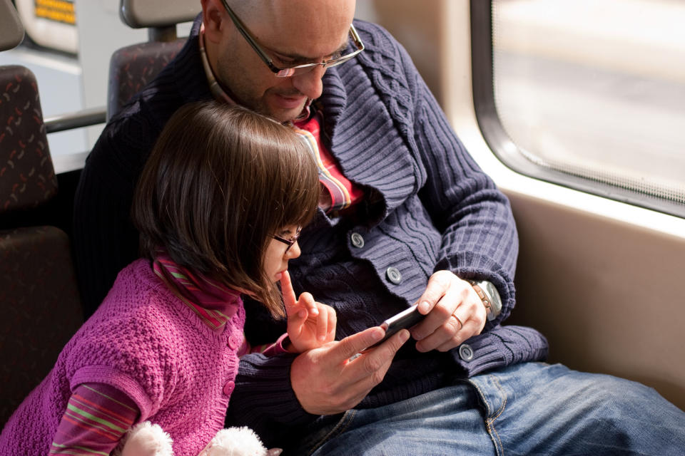 A father and daughter watching a video on a smartphone.