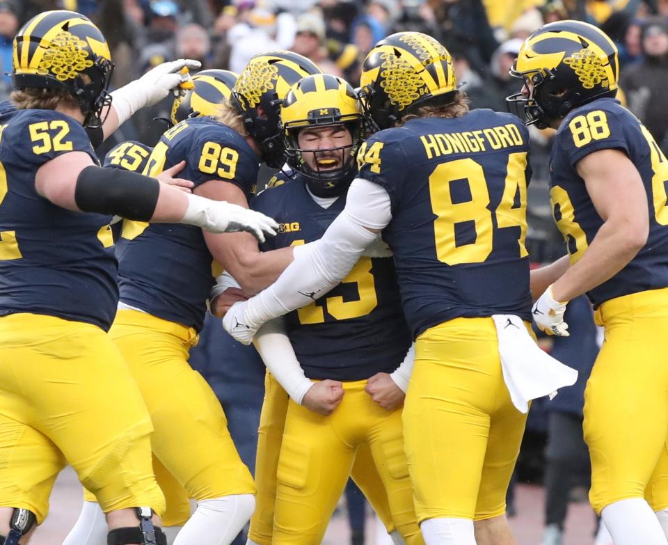 Michigan Wolverines kicker Jake Moody (13) celebrates with tight end Joel Honigford and other teammates after Moody kicked the winning field goal against Illinois to seal a 19-17 win at Michigan Stadium, Saturday, Nov. 19, 2022.