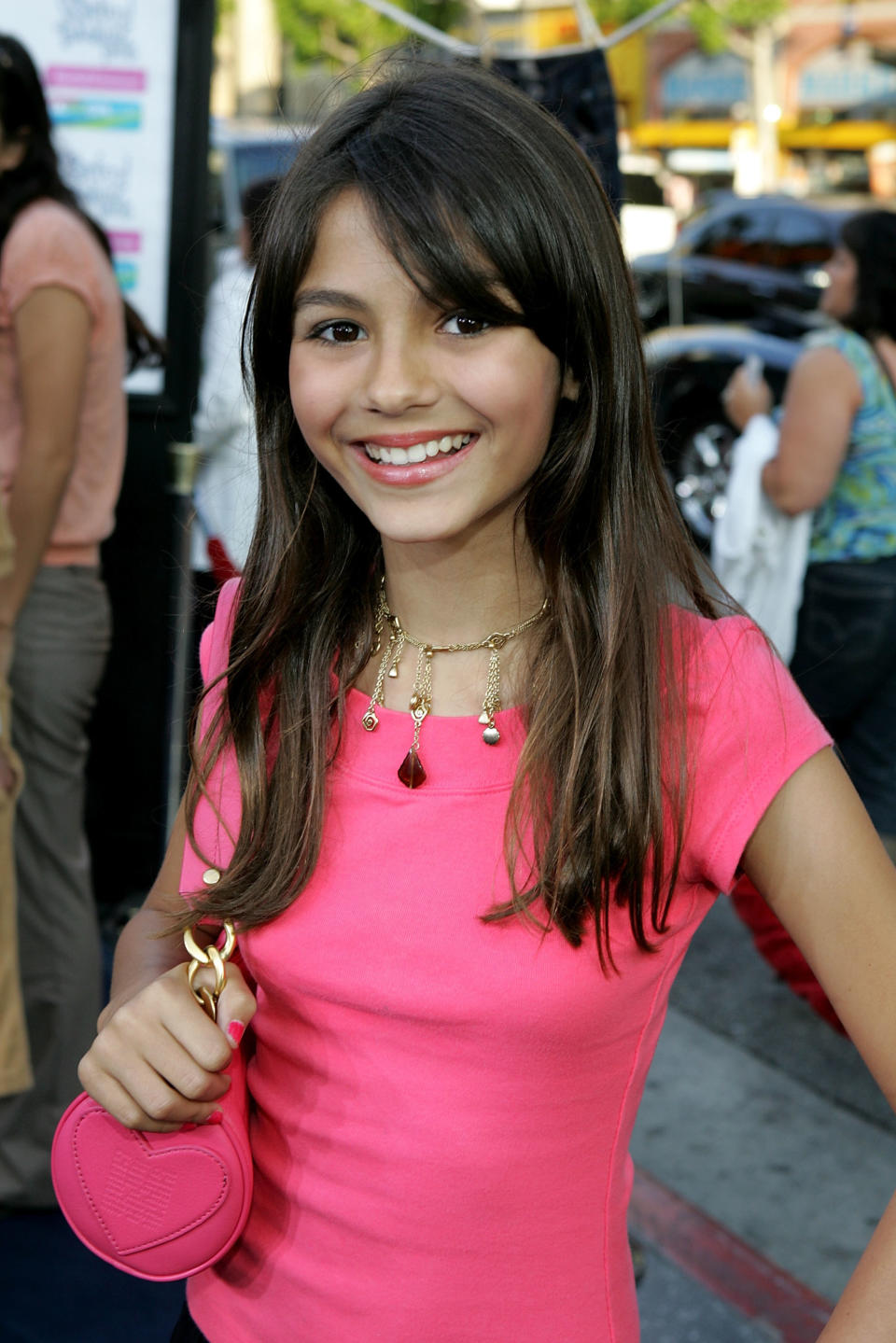 Smiling Victoria in a short-sleeved bright top and dangly necklace