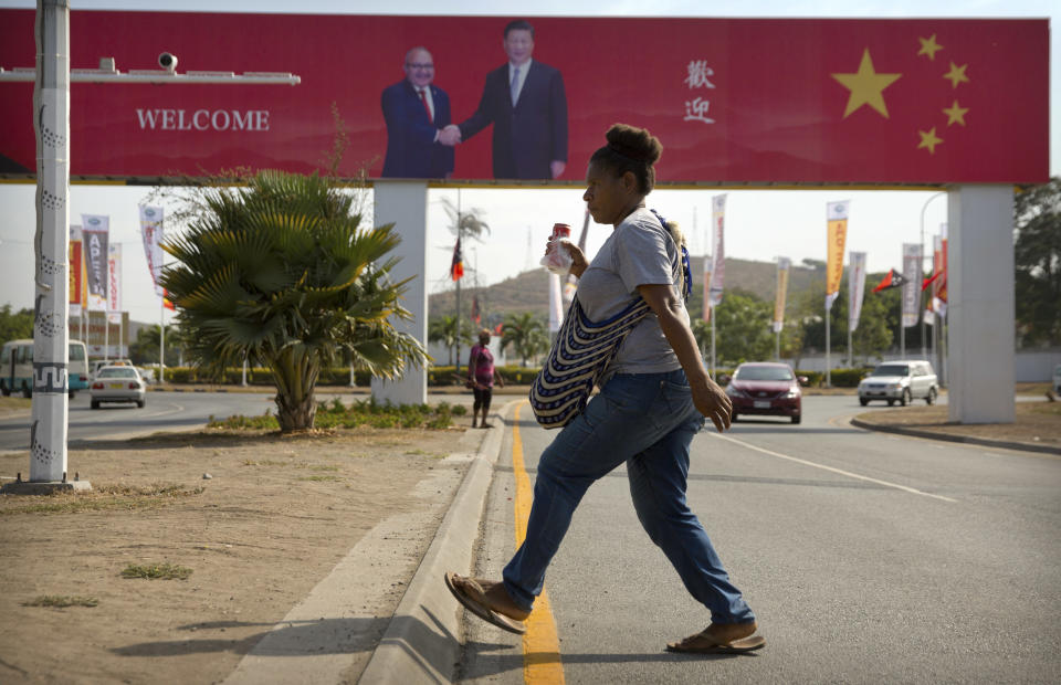 In this Nov. 15, 2018, photo, a woman crosses the street near a billboard commemorating the state visit of Chinese President Xi Jinping in Port Moresby, Papua New Guinea. As world leaders arrive in Papua New Guinea for a Pacific Rim summit, the welcome mat is especially big for China’s President Xi Jinping. With both actions and words, Xi has a compelling message for the South Pacific’s fragile island states, long both propped up and pushed around by U.S. ally Australia: they now have a choice of benefactors. (AP Photo/Mark Schiefelbein)