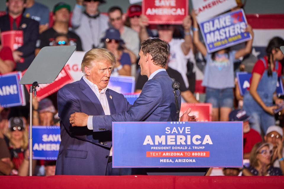 Former president Donald Trump shakes hands with U.S. Senate candidate Blake Masters after inviting Masters back up to the stage during Trump's rally at Legacy Sports Park in Mesa on Sunday, Oct. 9, 2022.