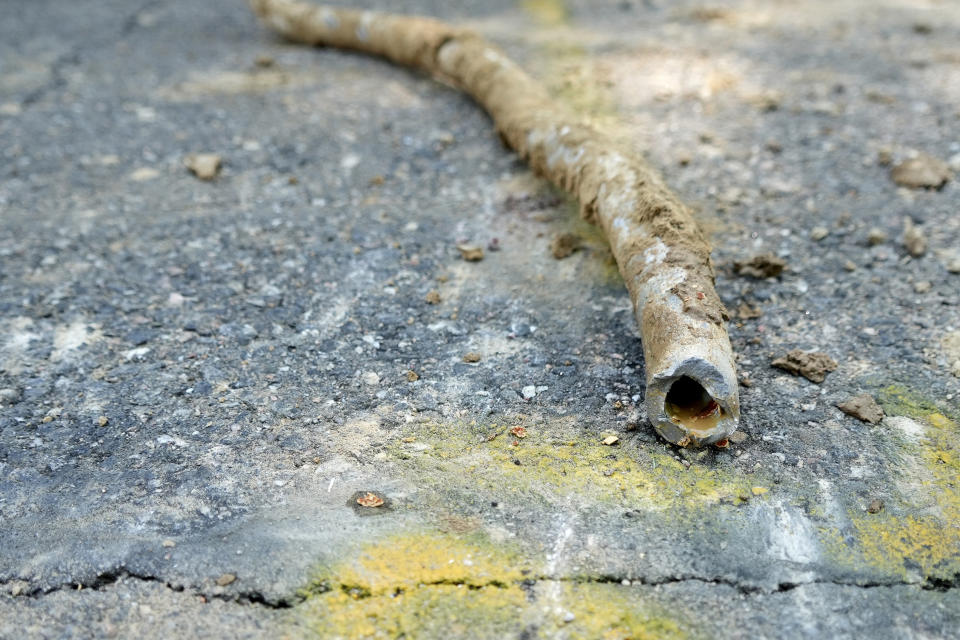 FILE - In this Thursday, June 17, 2021 file photo, a lead water service line from 1927 lies on the surface of a residential street after being removed in Denver. On Thursday, Oct. 28, 2021, U.S. health officials changed their definition of lead poisoning in young children — a move expected to more than double the number of kids with worrisome levels of the toxic metal in their blood. The more stringent standard announced by the Centers for Disease Control and Prevention means the number of children ages 1 to 5 considered to have high blood lead levels will grow from about 200,000 to about 500,000. (AP Photo/Brittany Peterson, File)