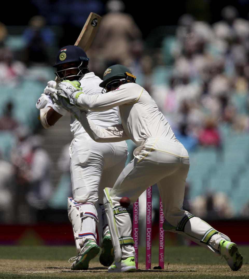India's Cheteshwar Pujara, left, turns to see a shot he played past Australia's Tim Paine go for 4 runs on day 2 during their cricket test match in Sydney, Friday, Jan. 4, 2019. (AP Photo/Rick Rycroft)