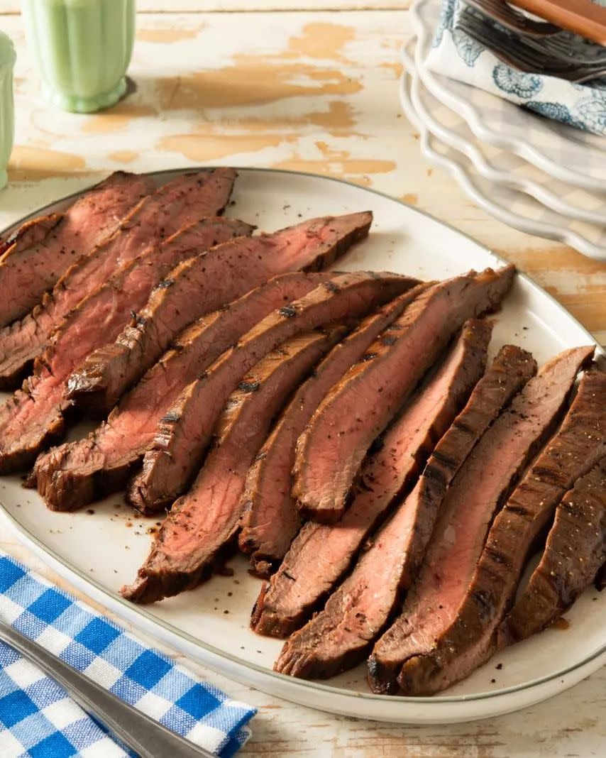 grilled flank steak on white platter blue napkin