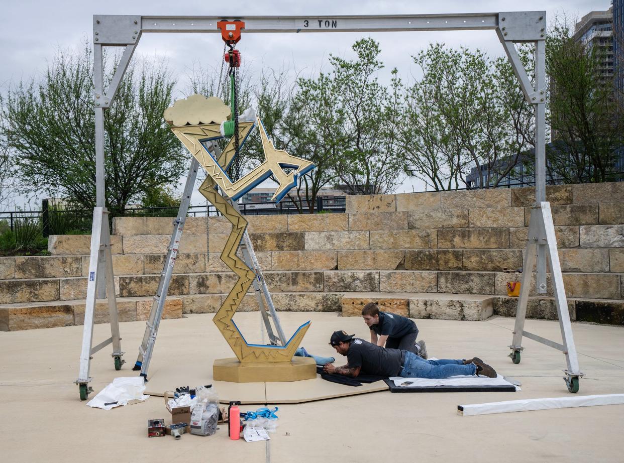 Visual Fine Arts Services employees Chris Dennis and Abi Waller help install artist Guadalupe Maravilla's art installation, "Serpent of the Sun and the Moon," at Waterloo Park.