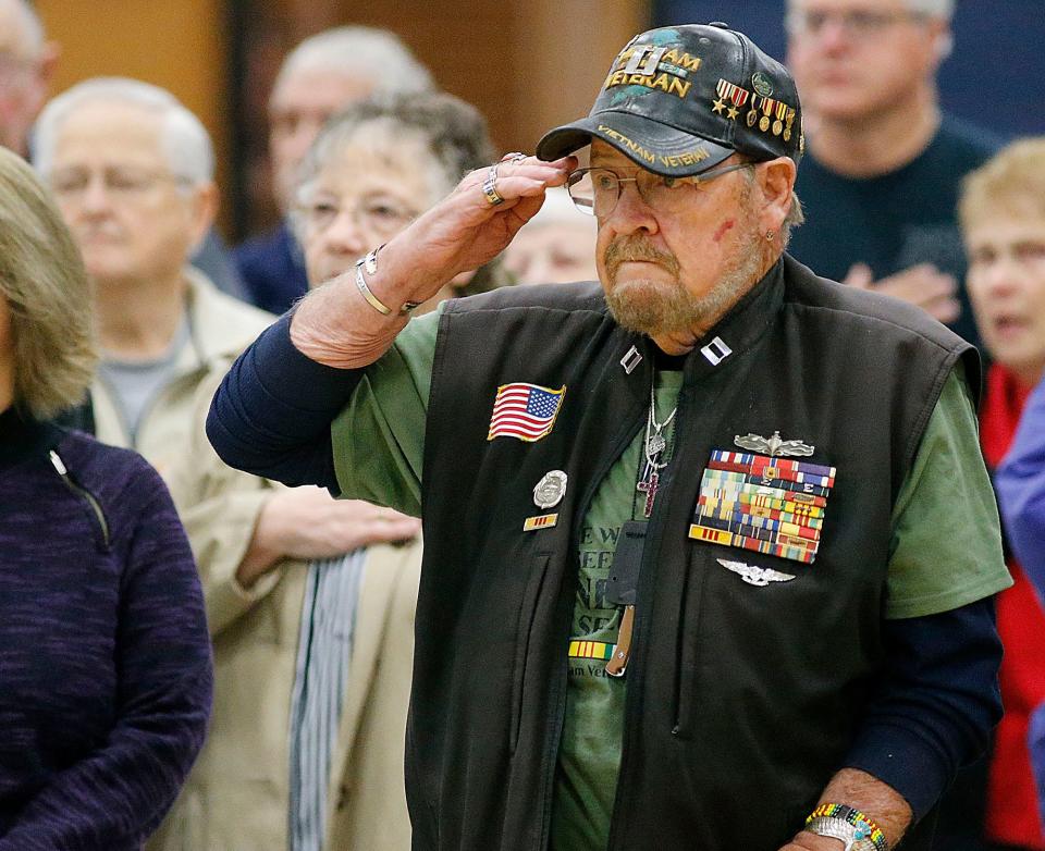 U.S. Navy and Coast Guard veteran Larry Salyers salutes during the singing of the national anthem at Hillsdale Local's Veterans Day program.