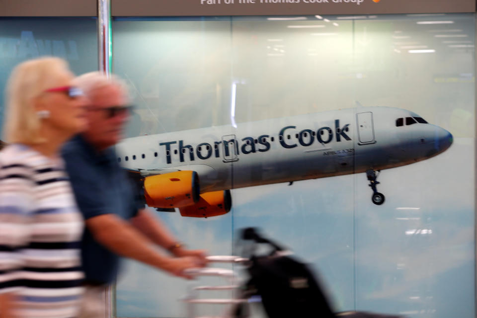 Passengers at Mallorca airport walk past a Thomas Cook ad. Photo: Enrique Calvo/Reuters