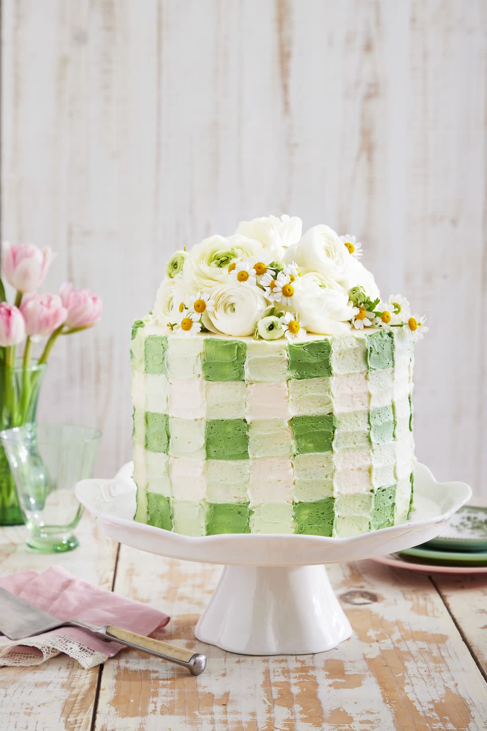 coconut cream cake with light green gingham patterned frosting and fresh white flowers on top