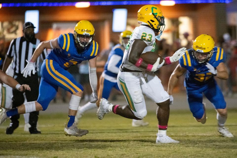 Catholic's Nigel Nelson (No. 23) finds running room against the Gulf Breeze defense during Friday's high school football matchup.