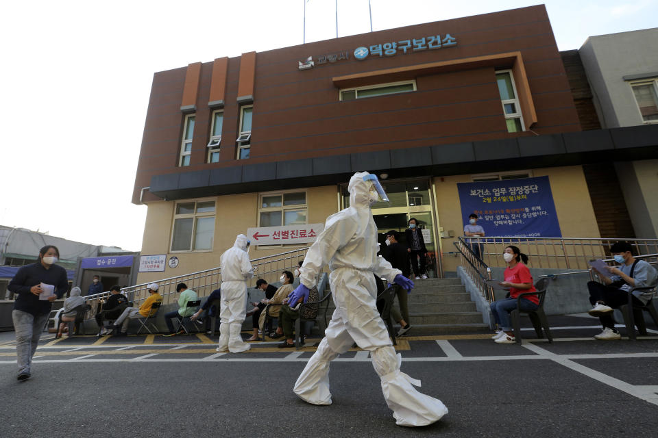 A health official wearing protective gear passes by people sitting and waiting for test for the new coronavirus at a public health center in Goyang, South Korea, Thursday, May 28, 2020. South Korea on Thursday reported its biggest jump in coronavirus cases in more than 50 days, a setback that could erase some of the hard-won gains that have made it a model for the rest of the world. (AP Photo/Ahn Young-joon)