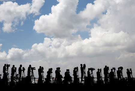 TV cameramen are silhouetted while they wait for the arrival of the Olympic flag during a ceremony to mark the arrival of the flag at Haneda airport in Tokyo, Japan, August 24, 2016. REUTERS/Kim Kyung-Hoon