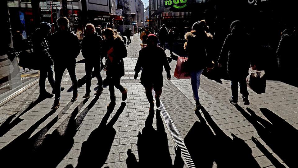 Passanten werfen in einer Kölner Fußgängerzone lange Schatten.