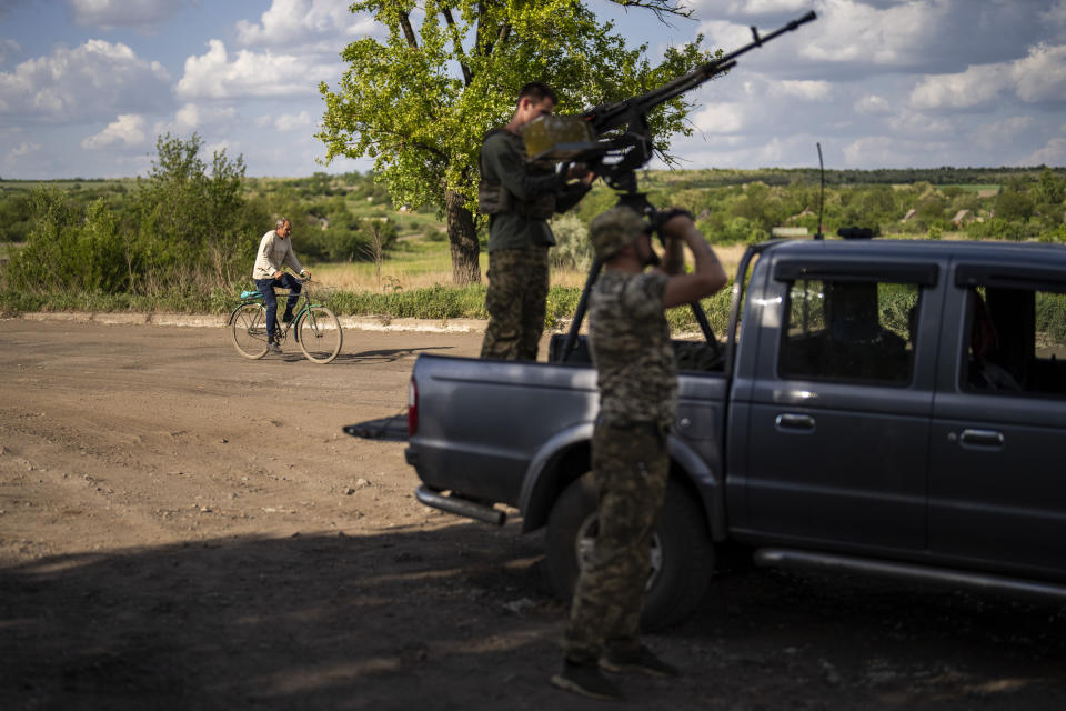 A local resident rides a bicycle past an Ukrainian army anti-drone unit, in Avdiivka direction, Ukraine, Monday, May 6, 2024. (AP Photo/Francisco Seco)