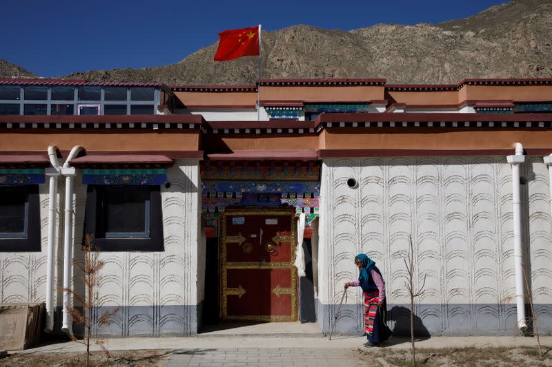 A woman walks in a purpose built village for Tibetans who have been relocated from high-alitude locations in Gongga County