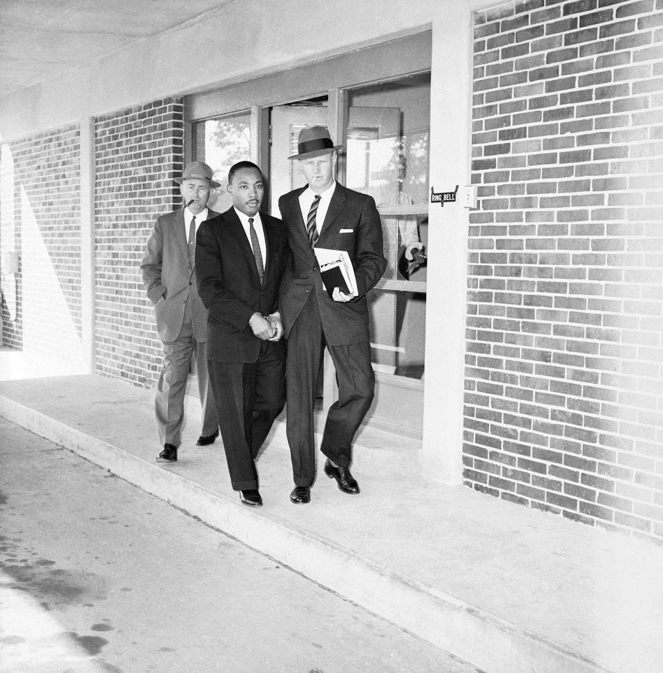 Rev. Martin Luther King Jr. escorted from Fulton County, Ga., jail by two unidentified officers as he is taken to neighboring DeKalb County courthouse for a traffic hearing on Oct. 25, 1960.