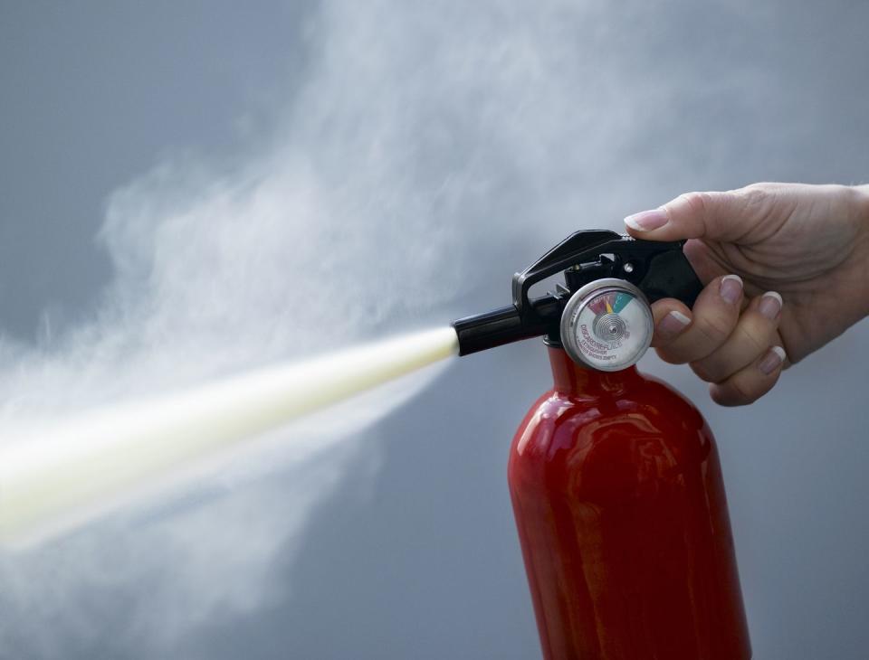 woman using fire extinguisher, close up