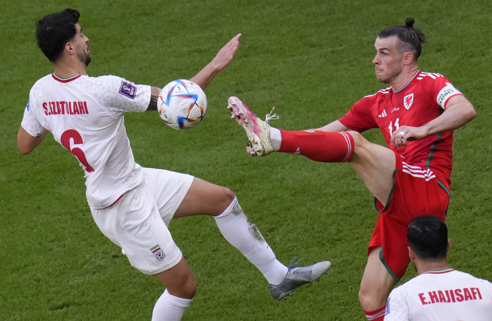 Wales' Gareth Bale, right, duels for the ball with Iran's Saeid Ezatolahi during the World Cup group B soccer match between Wales and Iran, at the Ahmad Bin Ali Stadium in Al Rayyan , Qatar, Friday, Nov. 25, 2022. (AP Photo/Manu Fernandez)