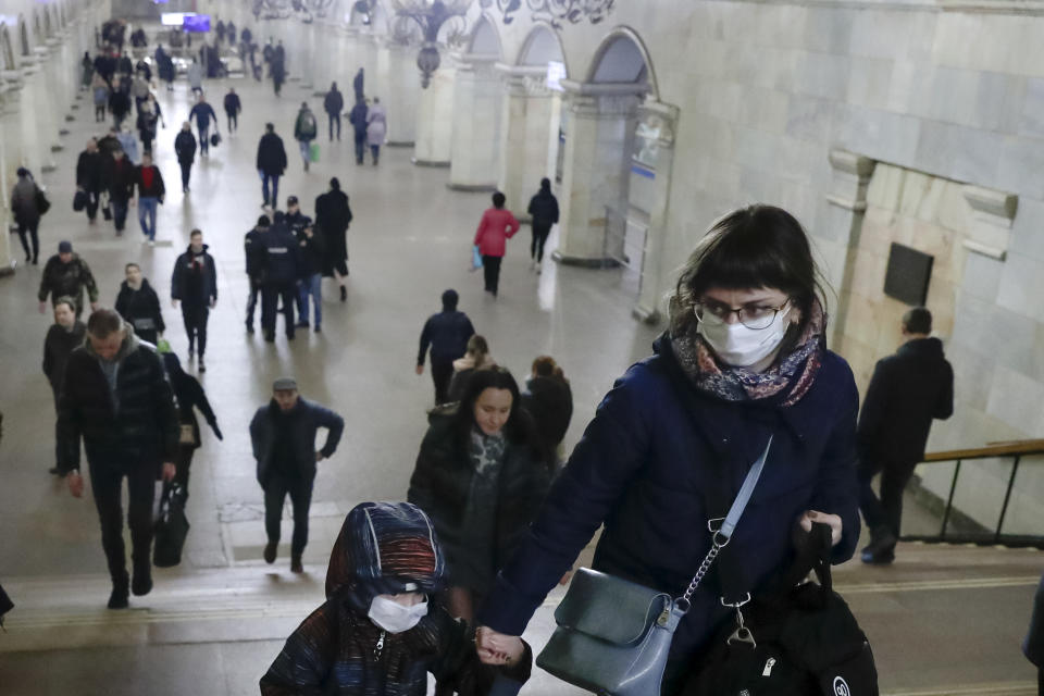 A woman with her child wear medical masks walk inside the Komsomolskaya Metro (subway) station in Moscow, Russia, Wednesday, March 18, 2020. Authorities in Russia are taking vast measures to prevent the spread of the disease in the country. The measures include closing the border for all foreigners, shutting down schools for three weeks, sweeping testing and urging people to stay home. For most people, the new coronavirus causes only mild or moderate symptoms. For some it can cause more severe illness. (AP Photo/Pavel Golovkin)