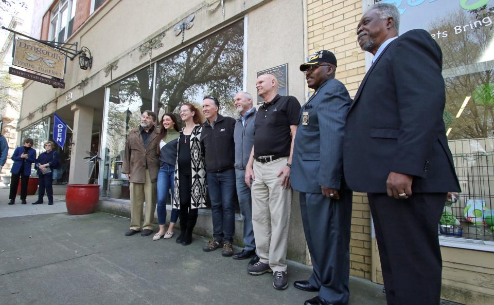 City Manager Rick Howell, center, has a group photo taken during a surprise celebration for him held Thursday afternoon, March 16, 2023, outside the Dragonfly Wine Market in Shelby.
