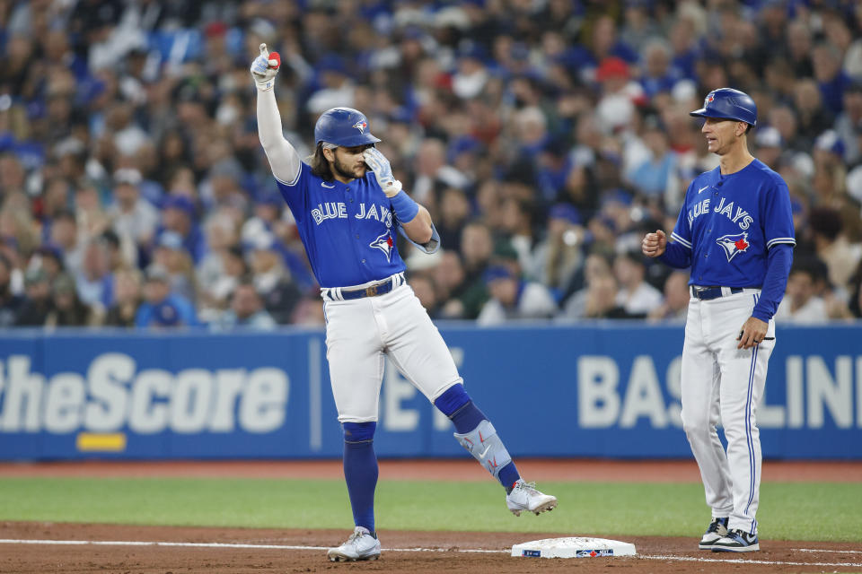 Toronto Blue Jays Bo Bichette, left, celebrates after his single against the New York Yankees in the fourth inning of baseball game action in Toronto, Monday, Sept. 26, 2022. (Cole Burston/The Canadian Press via AP)