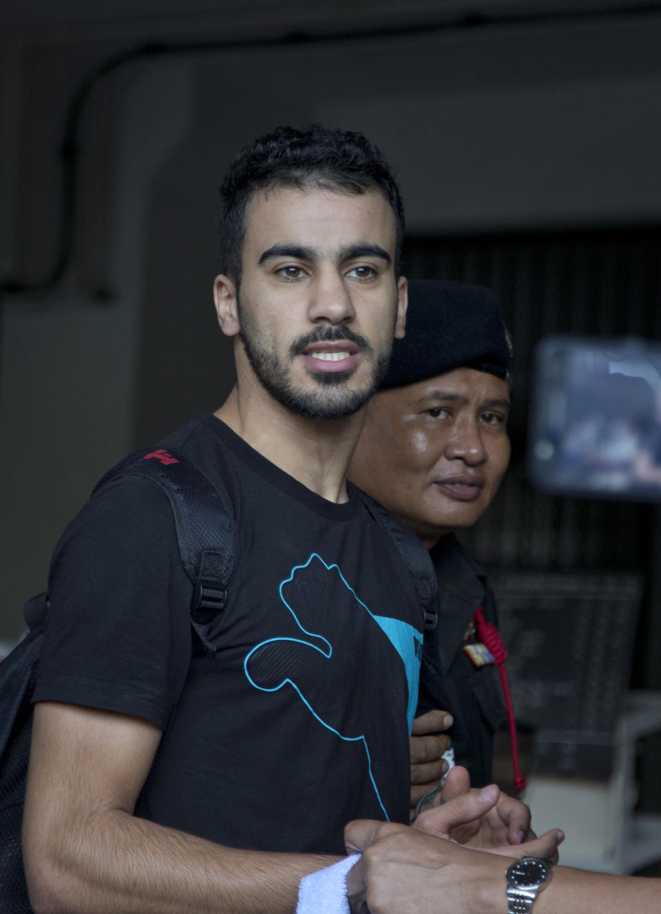 Bahraini football player Hakeem al-Araibi, left, gestures as he is brought in to a court in Bangkok, Thailand, Tuesday, Dec. 11, 2018. A Thai court has ruled that the soccer player who holds refugee status in Australia can be held for 60 days pending the completion of an extradition request by Bahrain, the homeland he fled four years ago on account of alleged political persecution. (AP Photo/Gemunu Amarasinghe)