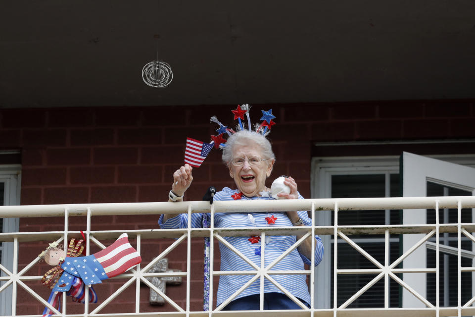 FILE - In this March 20, 2020, file photo, a resident of the Lambeth House, where a cluster of COVID-19 has formed, reacts from her balcony as opera singers Irini Hymel and Bryan Hymel sing to the quarantined residents in New Orleans. As coronavirus cases spike ever higher in Louisiana, the state's nursing homes, assisted living sites and adult residential care facilities are showing more and more "clusters" of the virus, but the full scale of the outbreak at those sites remains uncertain. (AP Photo/Gerald Herbert, File)