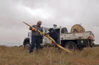 In this Thursday, May 9, 2019 photo Justin Foutz, left, a journeyman lineman with Piqua Power System in Piqua, Ohio, and Vernon Begay, right, with the Navajo Tribal Utility Authority put away a tool used to send power to a home in Kaibeto, Ariz., on the Navajo Nation. An ambitious project to connect homes to the electric grid on the country's largest American Indian reservation is wrapping up. Utility crews from across the U.S. have volunteered their time over the past few weeks to hook up about 300 homes on the Navajo Nation. (AP Photo/Felicia Fonseca)