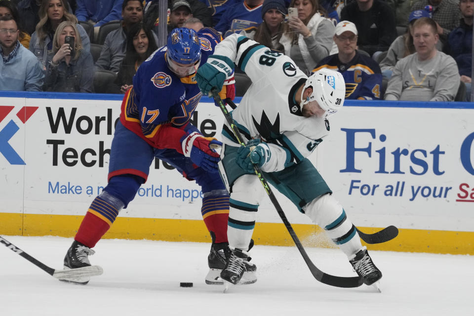 St. Louis Blues' Josh Leivo (17) and San Jose Sharks' Mario Ferraro (38) battle for a loose puck during the third period of an NHL hockey game Thursday, March 9, 2023, in St. Louis. (AP Photo/Jeff Roberson)