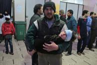 A Syrian man carries a wounded child at a makeshift hospital in the rebel-held town of Douma, following air strikes by regime forces on Eastern Ghouta on February 20, 2018