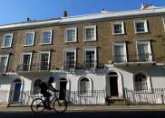 FILE PHOTO: A cyclist rides past houses on a street in Islington, London