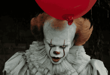Pennywise the clown from "It" with menacing expression, holding a red balloon