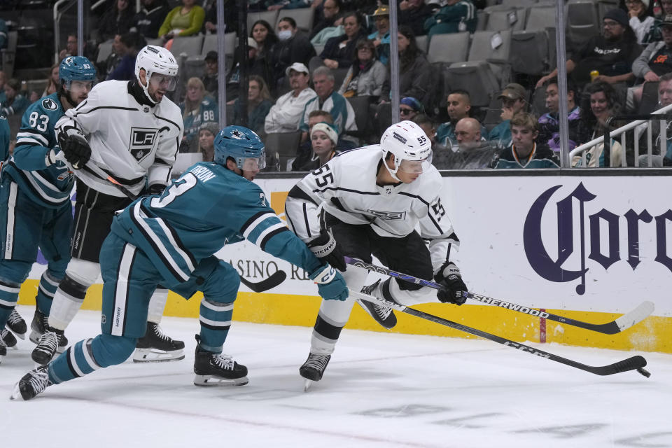 San Jose Sharks defenseman Henry Thrun, left, reaches for the puck next to Los Angeles Kings right wing Quinton Byfield (55) during the second period of an NHL hockey game in San Jose, Calif., Tuesday, Dec. 19, 2023. (AP Photo/Jeff Chiu)