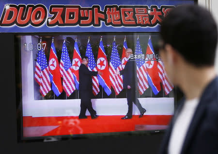 A passerby watches a TV broadcasting a news report on the summit between the U.S. and North Korea, in Tokyo, Japan, June 12, 2018. REUTERS/Issei Kato