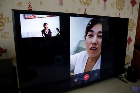 Bi Fenghua, 66, and her daughter-in-law are seen on the screen of a TV set as she performs the video chat function provided by Lanchuang's elderly care system in Weifang