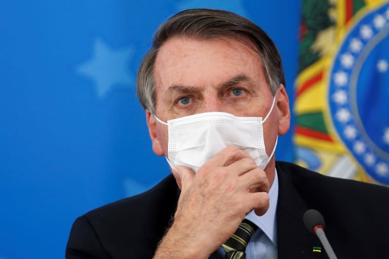 Brazil's President Jair Bolsonaro wearing a protective face masks reacts during a news conference to announce measures to curb the spread of the coronavirus disease (COVID-19) in Brasilia