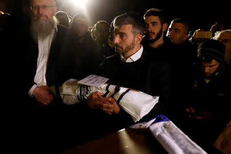 A man holds the body of a baby who died after being delivered prematurely following a shooting attack near the Israeli settlement of Ofra, in the Israeli-occupied West Bank, during his funeral at Mount of Olives cemetery in Jerusalem December 12, 2018. REUTERS/Ronen Zvulun