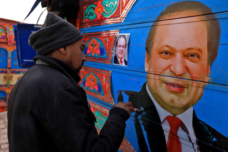 Sohail Ghuri applies the final touches to a portrait of former PM Sharif on wooden planks in the back of a truck at a workshop, in Peshawar