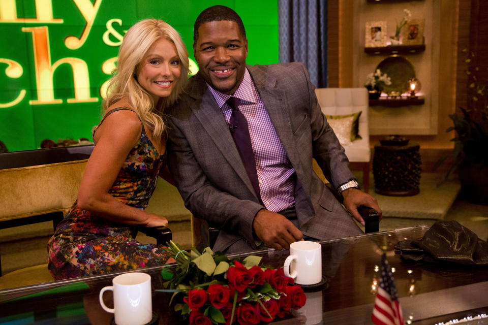 Former football player Michael Strahan, right, poses Kelly Ripa on the set of the newly named "Live! with Kelly and Michael" on Tuesday, Sept. 4, 2012 in New York. Strahan joined the popular morning show as a permanent co-host on Tuesday, fulfilling a joking prophecy he made to Regis Philbin more than four years ago. The gap-toothed former New York Giant jogged onto the morning show set and picked up co-host Kelly Ripa in a bear hug, lifting her off her feet. He replaces Philbin, who left last November. Strahan was the survivor in a series of on-air tryouts of potential co-hosts since Philbin left, and his hiring has been an open secret for the past two weeks. (Photo by Charles Sykes/Invision/AP Images)