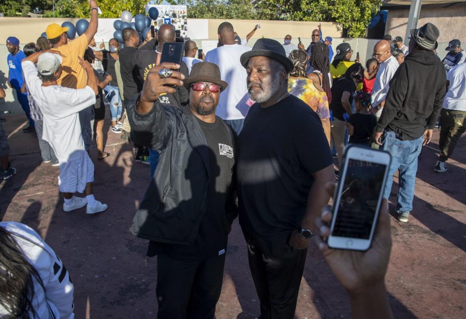 Leo "Pretty Boy" Smith, right, and an unidentified man, left, take a selfie during a vigil for Kody Scott.