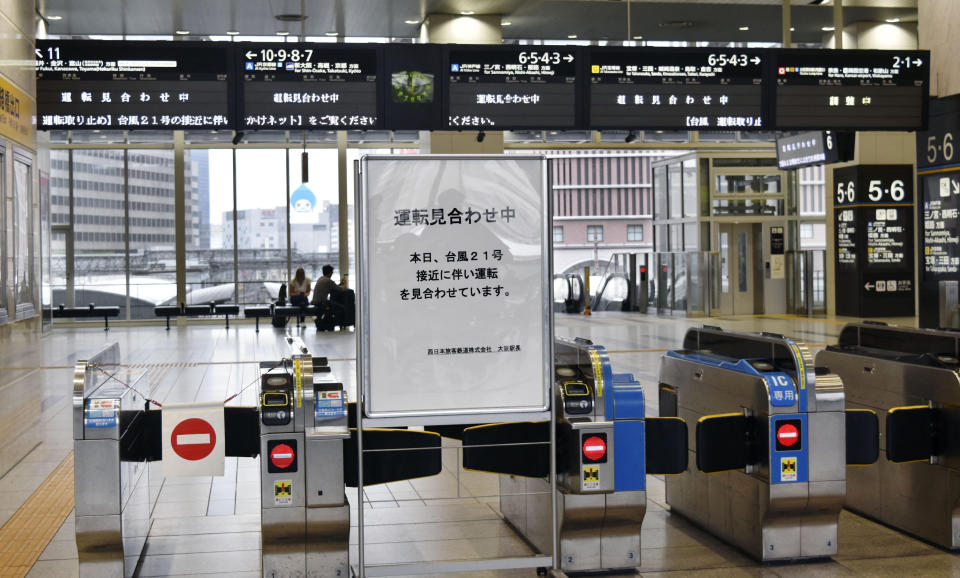 A notice informing cancelled trains is placed at the gates of Osaka Station in Osaka, western Japan, Tuesday, Sept. 4, 2018. Heavy rain and crashing surf were striking western Japan as powerful Typhoon Jebi neared its Pacific coast Tuesday, disrupting train service and air travel. (Kyodo News via AP)