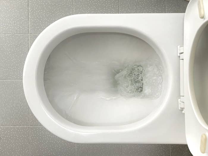 Top-down view of a toilet with water swirling in the bowl after being flushed