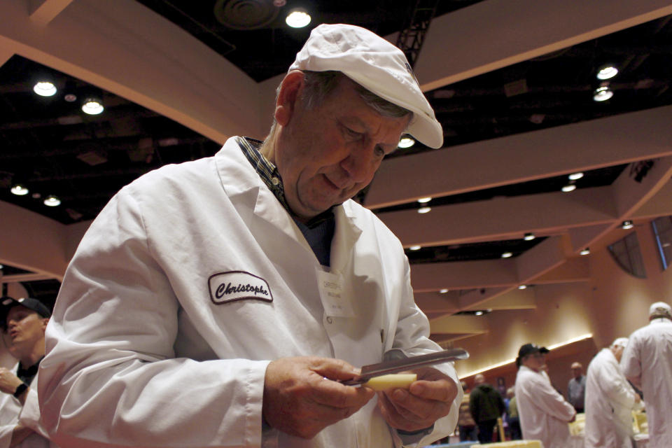 Judge Christophe Megevand inspects a piece of Gruyere cheese at the biennial World Championship Cheese Contest, Tuesday, March 3, 2020, at the Monona Terrace Convention Center in Madison, Wis. It's the largest technical cheese, butter and yogurt competition in the world. This year the competition had a record 3,667 entries from 26 nations. (AP Photo/Carrie Antlfinger)