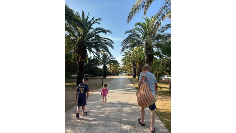 grandfather with two grandchildren walking down path 